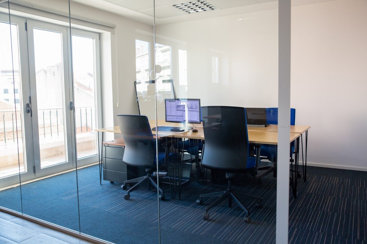 empty-boardroom-glass-wall-meeting-room-with-conference-table-shared-desk-team-workplaces-trading-graphs-monitor-office-interior-commercial-real-estate-concept 1
