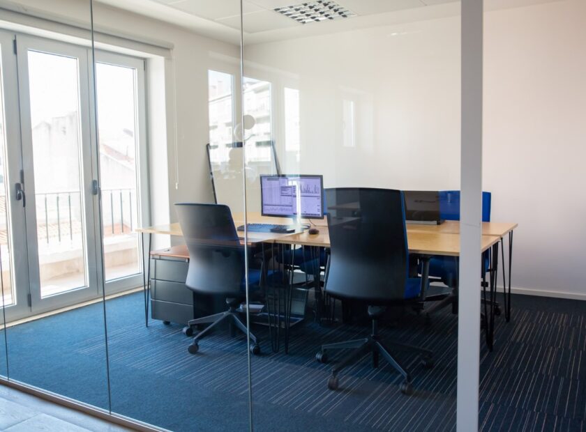empty-boardroom-glass-wall-meeting-room-with-conference-table-shared-desk-team-workplaces-trading-graphs-monitor-office-interior-commercial-real-estate-concept 1