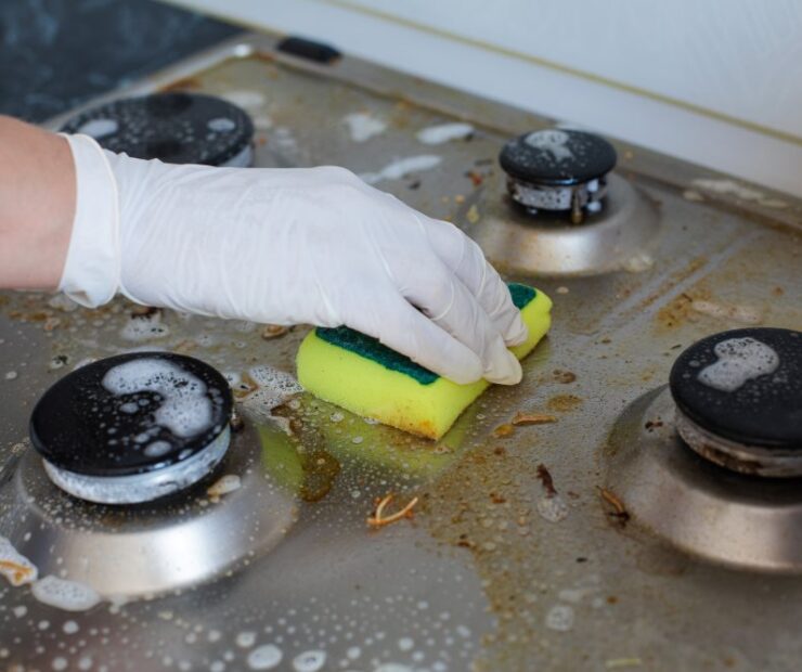 domestic-female-hand-wearing-gloves-cleaning-dirty-stove-after-cooking-using-sponge-washing-woman-housewife-enjoying-daily-household-closeup-top-view (1)
