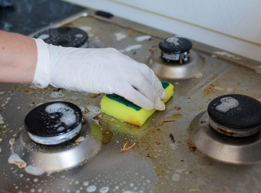 domestic-female-hand-wearing-gloves-cleaning-dirty-stove-after-cooking-using-sponge-washing-woman-housewife-enjoying-daily-household-closeup-top-view (1)